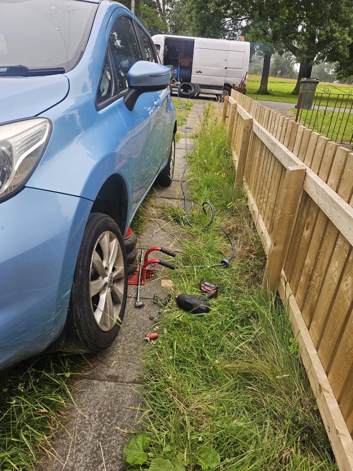 Mobile tyre fitting technician fitting a car tyre on a driveway in Glasgow